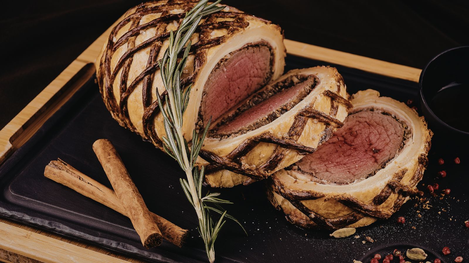 Plat de beef Wellington sur un plateau noir et en bois.