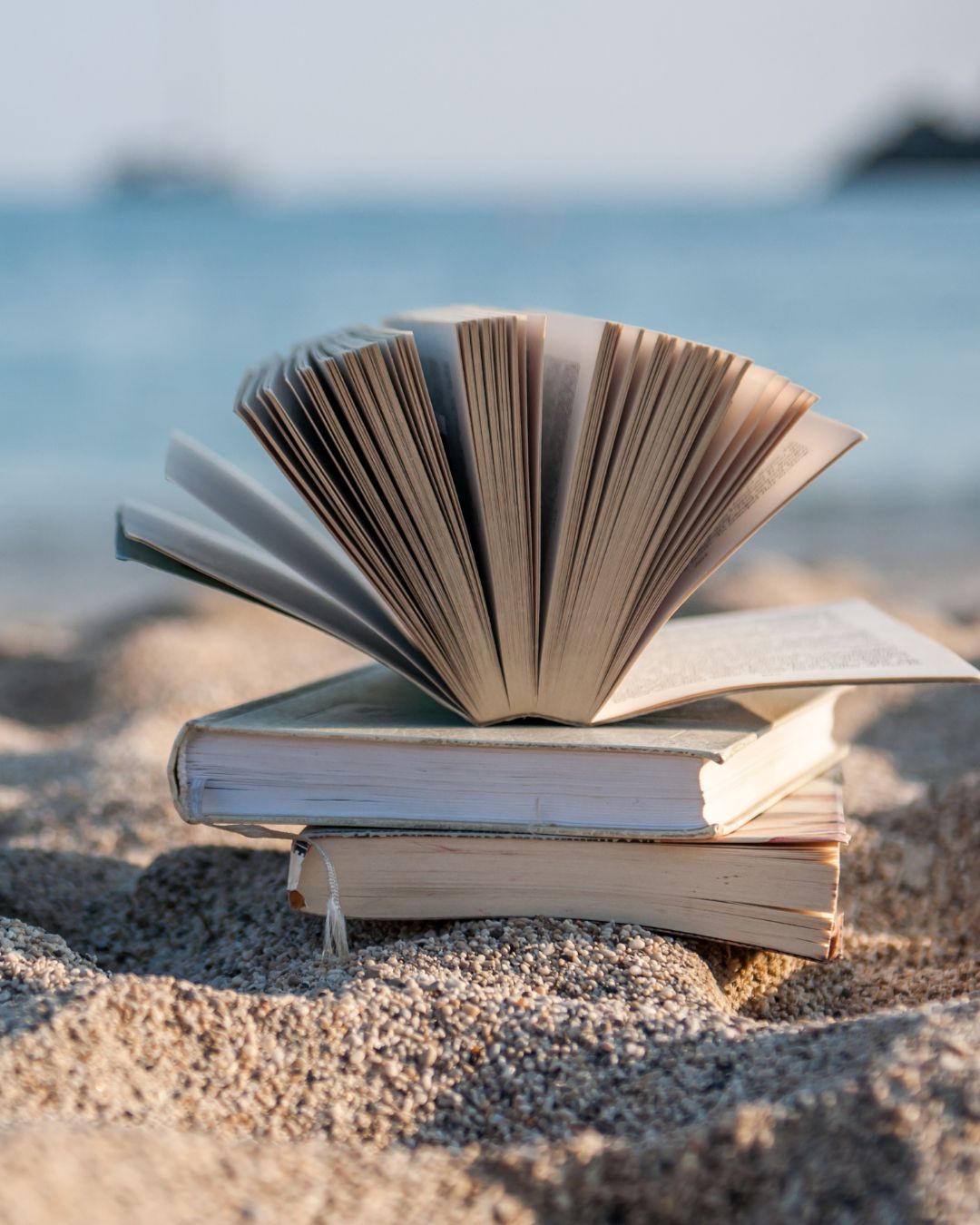 trois livres posés sur le sable sur une plage 