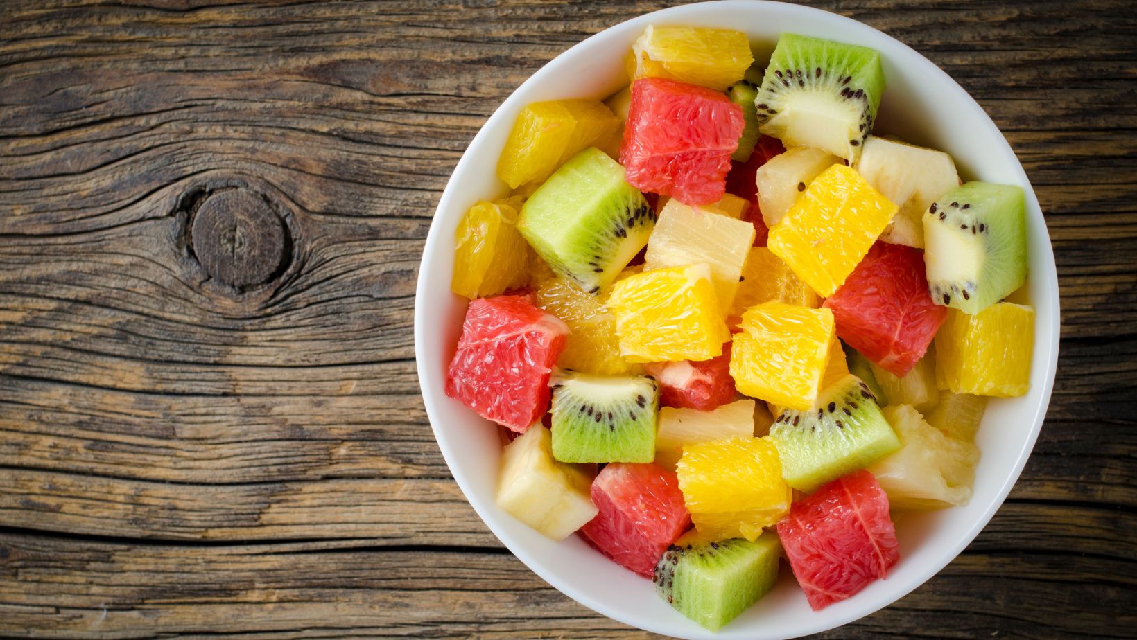 Coupelle contenant une salade de fruits : kiwis, oranges, bananes, pomelo, ananas