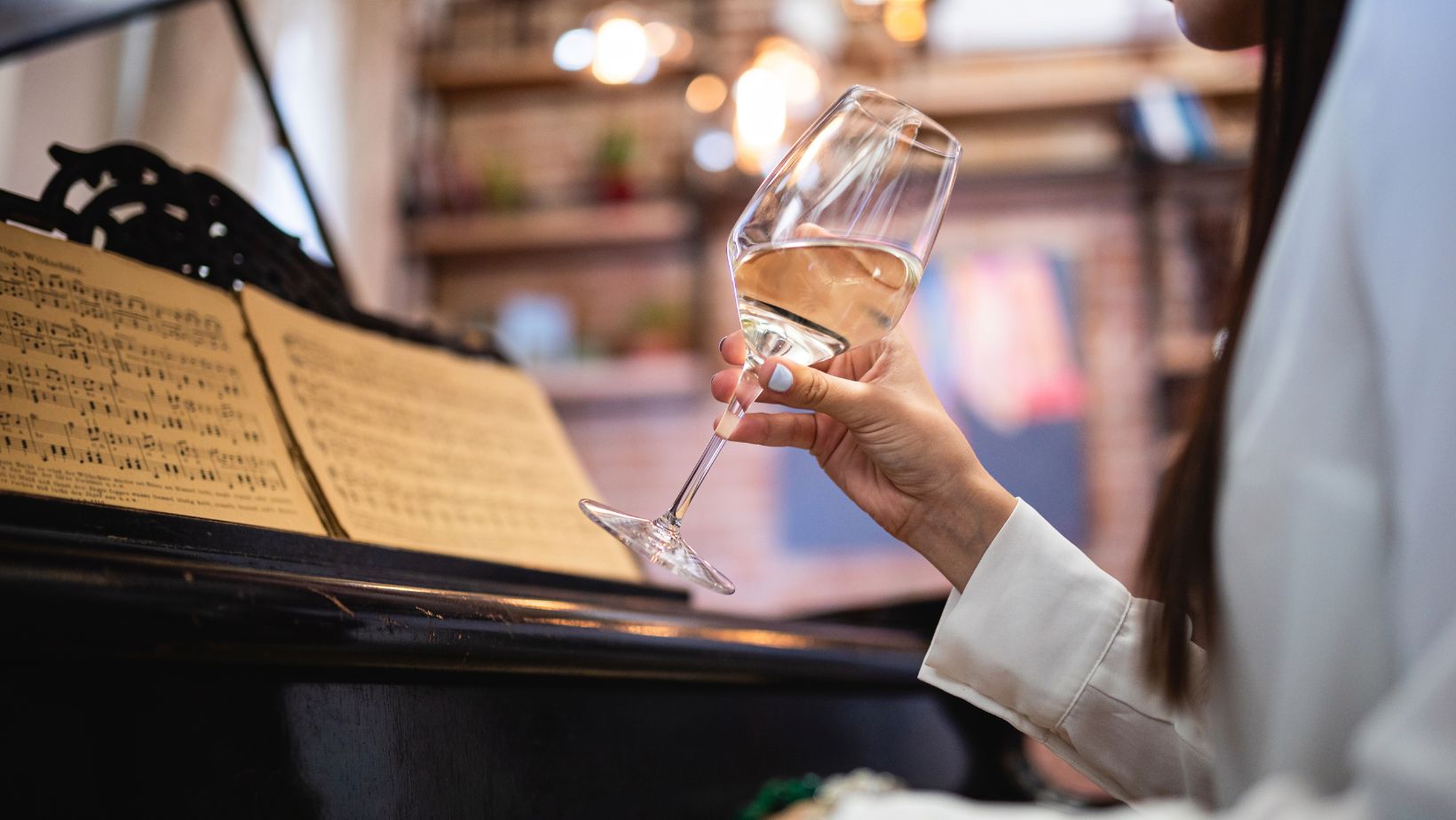 Art et vin une pianiste déguste un verre de vin blanc devant une partition de piano.
